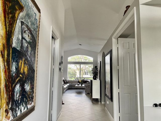 corridor featuring vaulted ceiling and light tile patterned floors