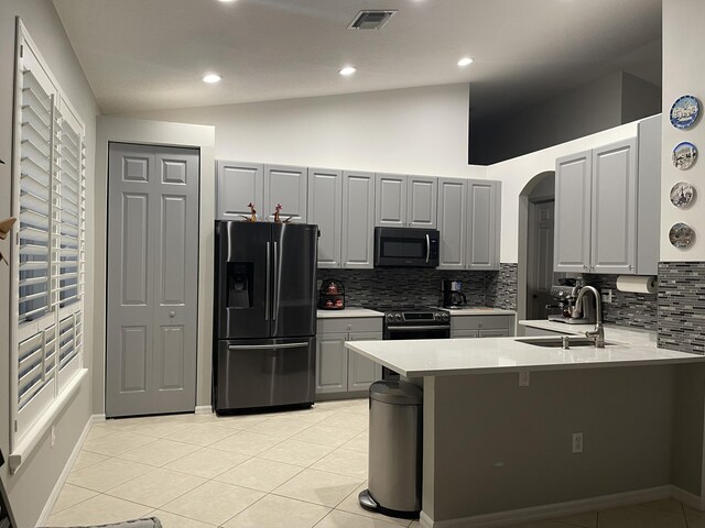 kitchen featuring lofted ceiling, black fridge, gray cabinets, a sink, and visible vents
