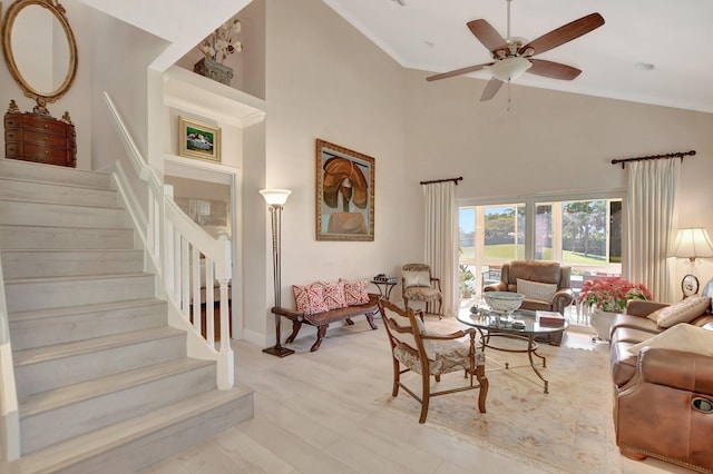 living room featuring light hardwood / wood-style floors, ceiling fan, and a towering ceiling