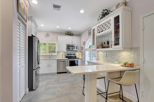 kitchen featuring sink, a kitchen bar, white cabinetry, and appliances with stainless steel finishes