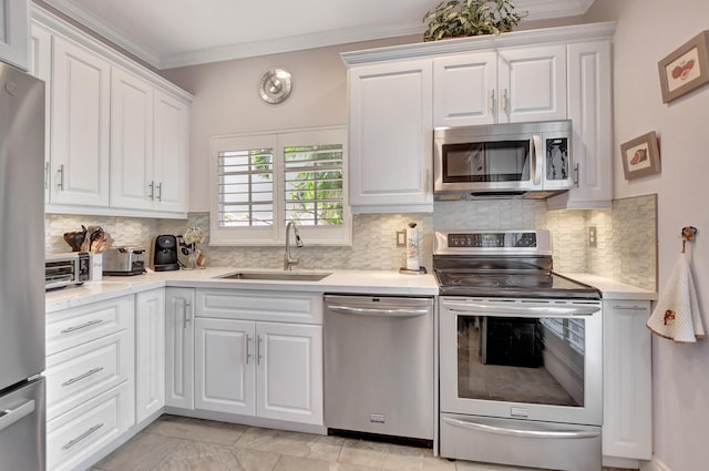 kitchen with backsplash, sink, white cabinets, and appliances with stainless steel finishes