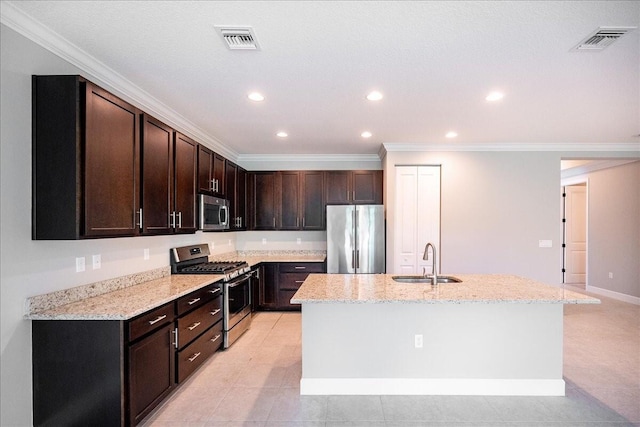 kitchen with dark brown cabinetry, sink, a kitchen island with sink, light tile patterned floors, and appliances with stainless steel finishes