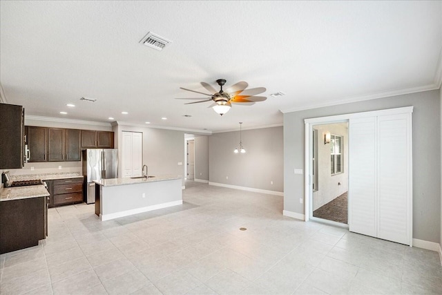 kitchen with stainless steel refrigerator, ceiling fan, sink, a kitchen island with sink, and dark brown cabinets