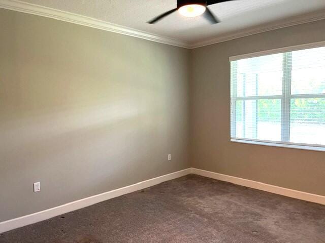 spare room with ceiling fan, dark carpet, and ornamental molding