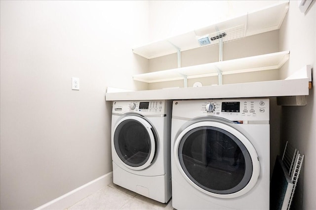 laundry room featuring separate washer and dryer, laundry area, baseboards, and light tile patterned flooring