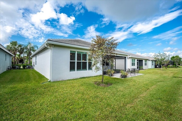 rear view of property featuring a lawn, a patio, stucco siding, and an attached garage