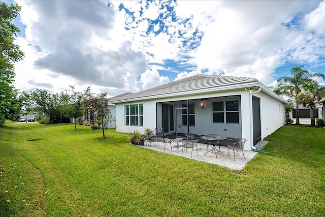 back of property with a yard, a tile roof, a patio, stucco siding, and a sunroom