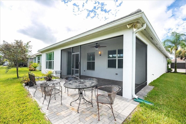 rear view of property featuring a sunroom, ceiling fan, a patio area, and a lawn