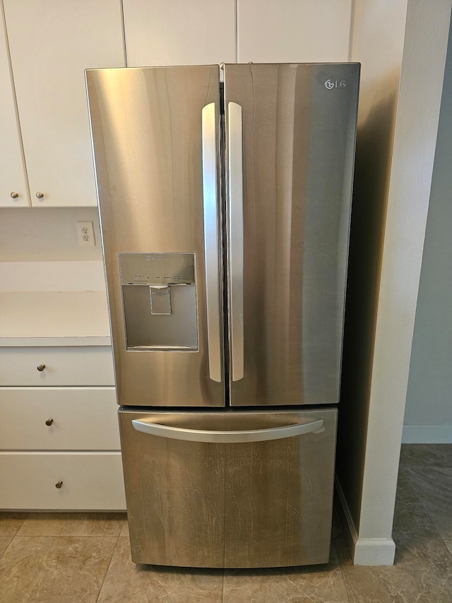 details featuring white cabinetry, light tile patterned floors, and stainless steel fridge with ice dispenser