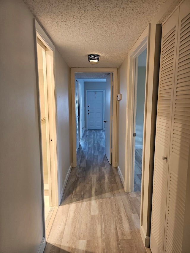 corridor featuring wood-type flooring and a textured ceiling