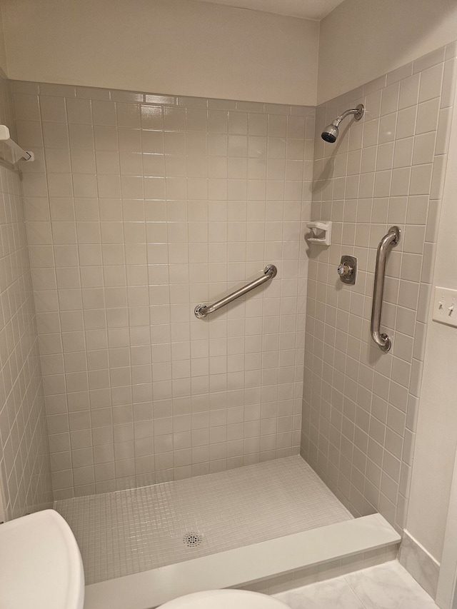 bathroom featuring tiled shower and toilet