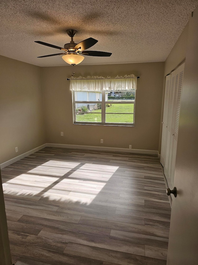 spare room with dark wood-type flooring, a textured ceiling, and ceiling fan