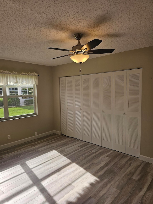 unfurnished bedroom with a textured ceiling, ceiling fan, and hardwood / wood-style floors