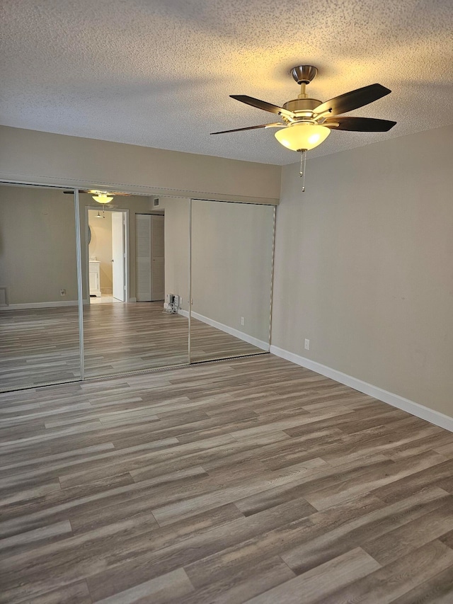 unfurnished bedroom featuring a textured ceiling, ceiling fan, hardwood / wood-style floors, and a closet