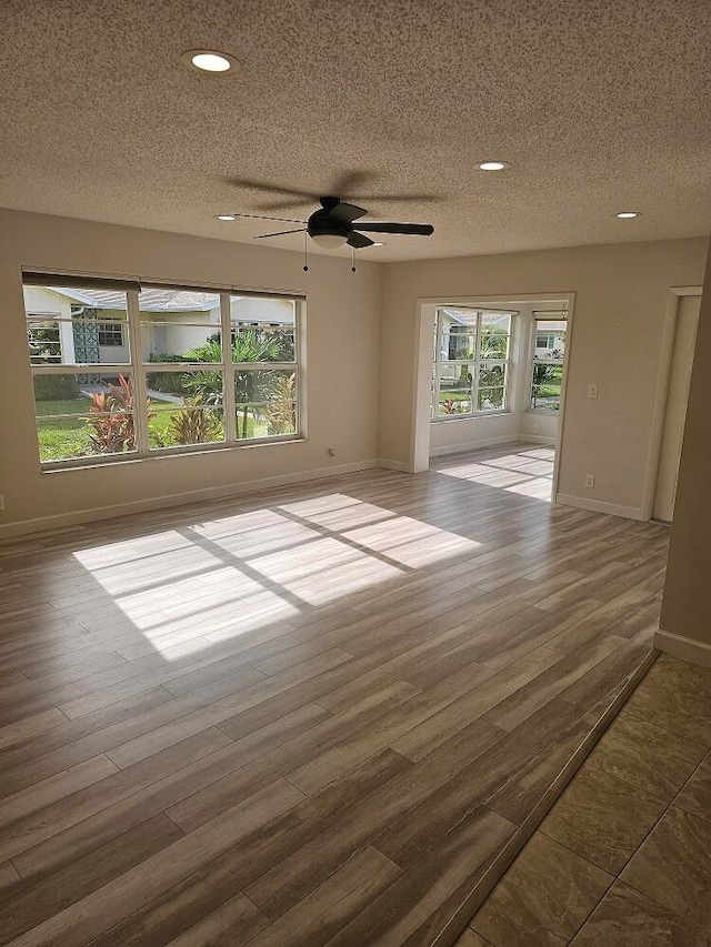 empty room featuring dark hardwood / wood-style floors, ceiling fan, and a textured ceiling