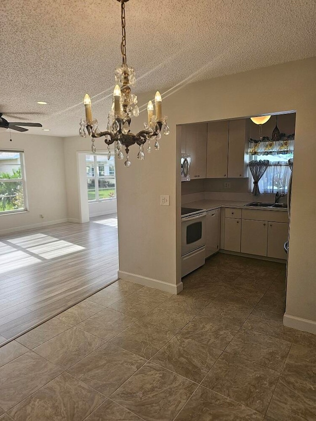 kitchen featuring hardwood / wood-style floors, sink, white electric range oven, a textured ceiling, and ceiling fan with notable chandelier