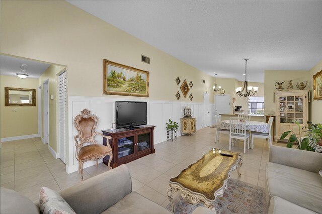 living room featuring visible vents, an inviting chandelier, a wainscoted wall, and light tile patterned flooring