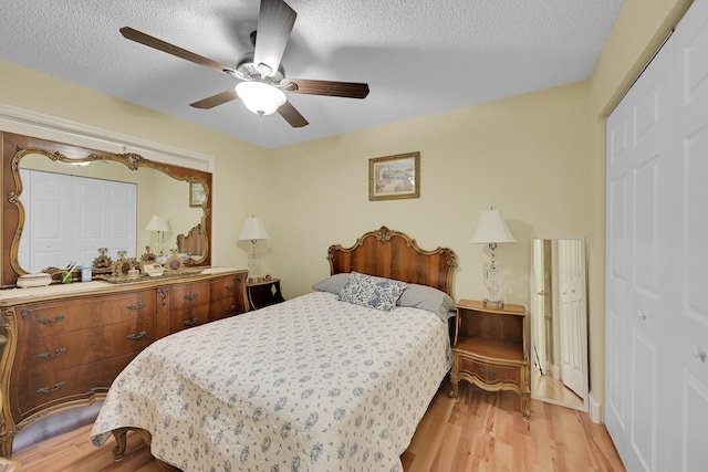bedroom with light wood-style flooring, ceiling fan, and a textured ceiling