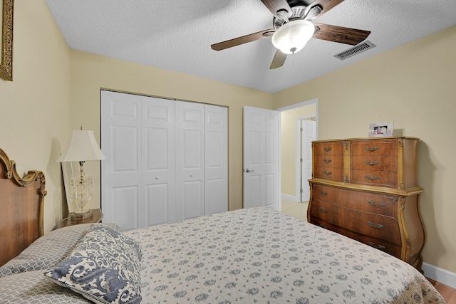 bedroom featuring a closet, baseboards, a textured ceiling, a ceiling fan, and visible vents