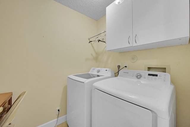laundry area with a textured ceiling, separate washer and dryer, baseboards, and cabinet space