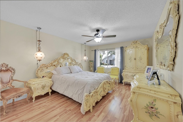 bedroom featuring light wood-style flooring, a textured ceiling, and a ceiling fan