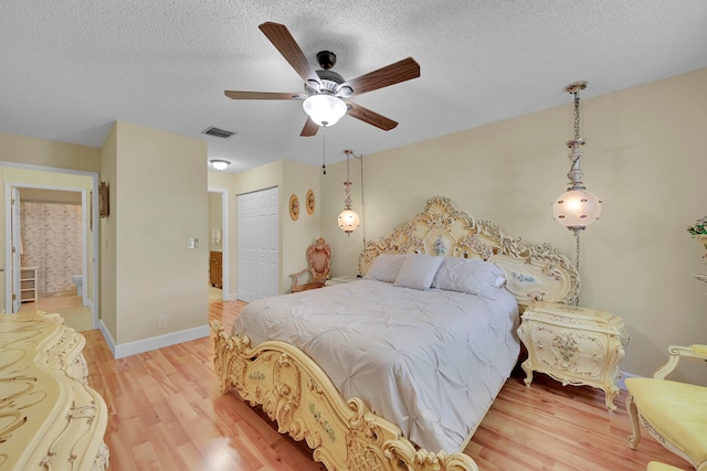 bedroom with light hardwood / wood-style flooring, a closet, a textured ceiling, and ceiling fan