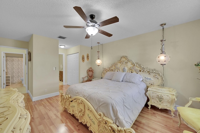 bedroom featuring light wood-style flooring, a textured ceiling, a closet, and visible vents