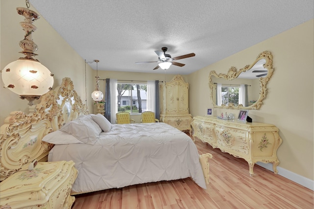 bedroom with ceiling fan, wood finished floors, and a textured ceiling