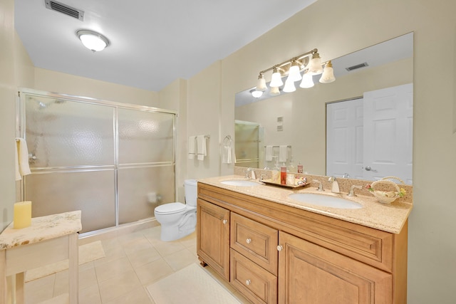 bathroom with tile patterned floors, toilet, an enclosed shower, and dual bowl vanity