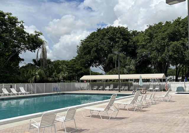 community pool with a patio area and fence