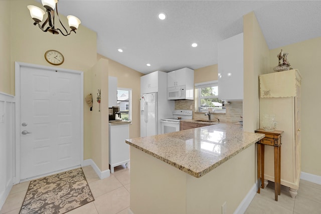 kitchen with white appliances, backsplash, light stone countertops, hanging light fixtures, and vaulted ceiling