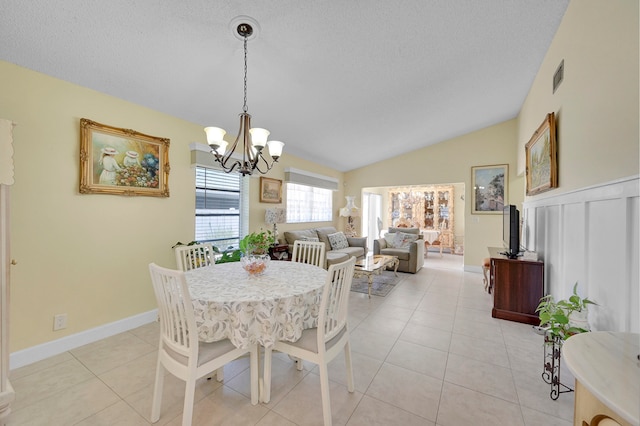 tiled dining room featuring lofted ceiling and a notable chandelier