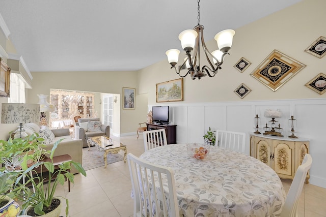 dining room with vaulted ceiling, an inviting chandelier, a wainscoted wall, and light tile patterned flooring