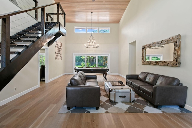 living room featuring wood ceiling, hardwood / wood-style flooring, billiards, an inviting chandelier, and a towering ceiling