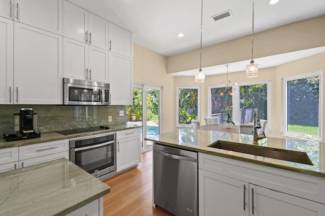 kitchen with sink, tasteful backsplash, hanging light fixtures, stainless steel appliances, and white cabinets