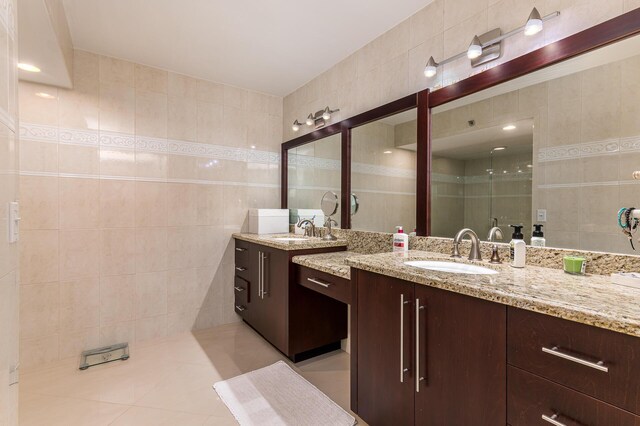 bathroom featuring vanity, a shower with door, tile patterned floors, and tile walls