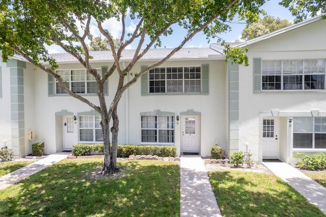 townhome / multi-family property with a front lawn and stucco siding