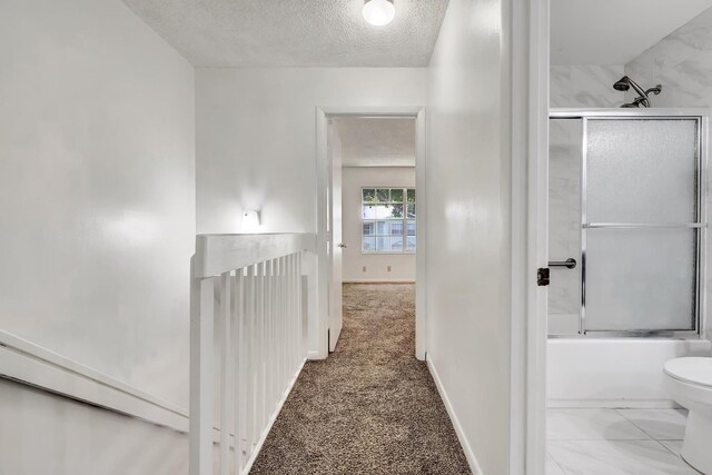 hallway with carpet and a textured ceiling