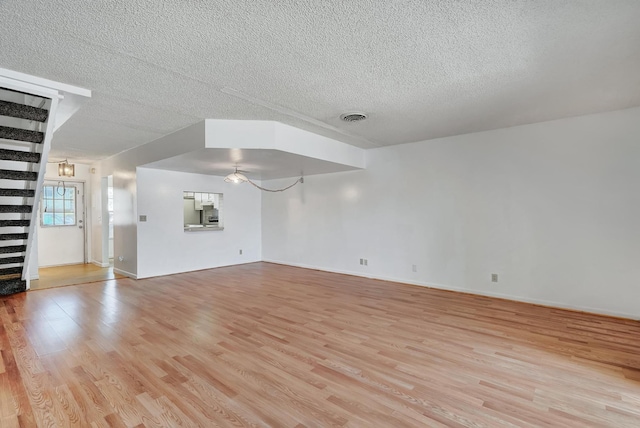 unfurnished living room featuring a textured ceiling and light wood-type flooring