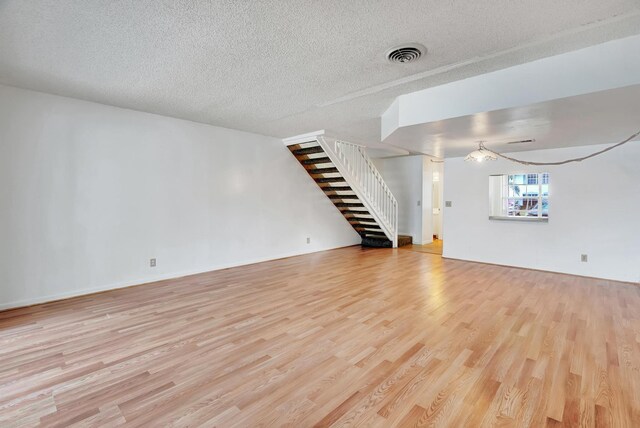 unfurnished living room featuring a textured ceiling and light wood-type flooring