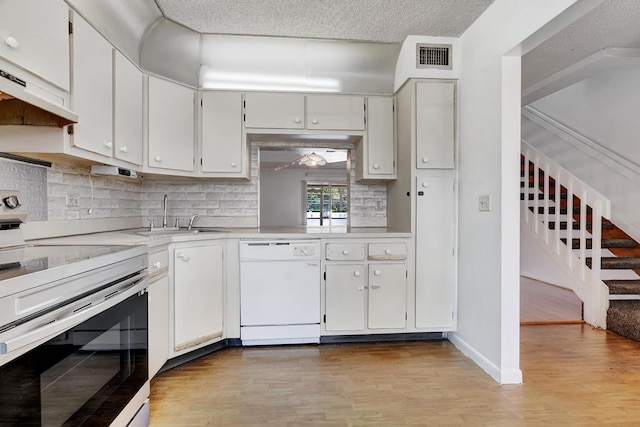 kitchen with light countertops, electric range, white cabinets, white dishwasher, and a sink