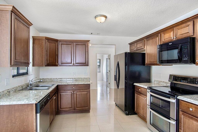 kitchen with sink, light stone counters, a textured ceiling, light tile patterned floors, and black appliances