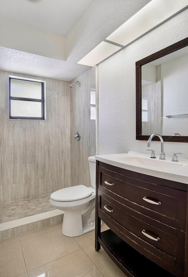 bathroom featuring tile patterned floors, vanity, toilet, and tiled shower