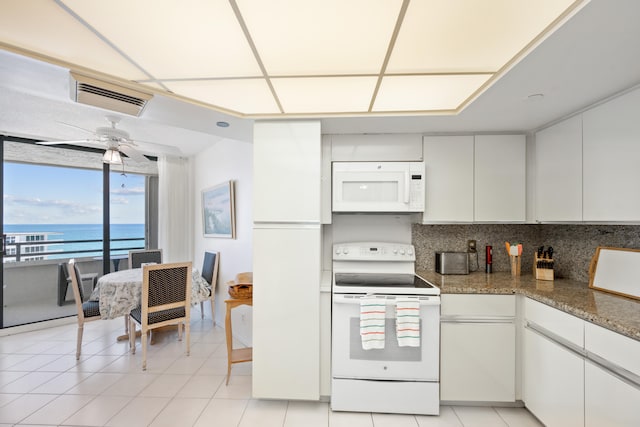 kitchen with light tile patterned flooring, ceiling fan, a water view, decorative backsplash, and white appliances