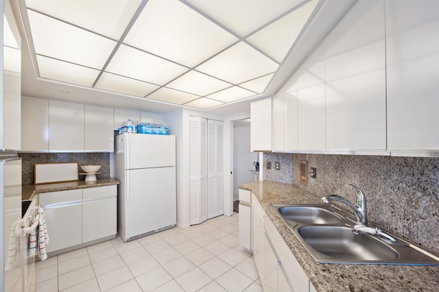 kitchen featuring white cabinets, white fridge, and tasteful backsplash