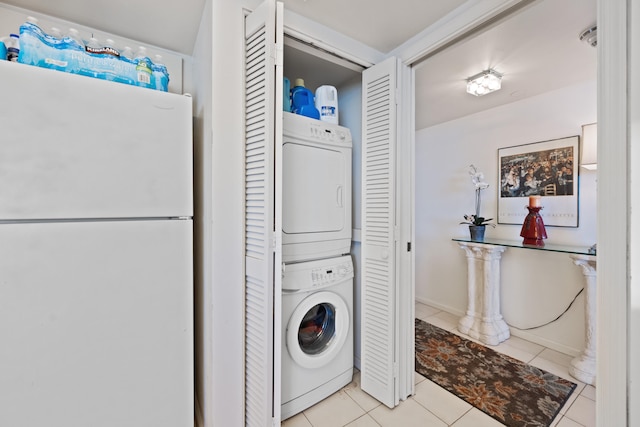 washroom with stacked washer and dryer and light tile patterned floors