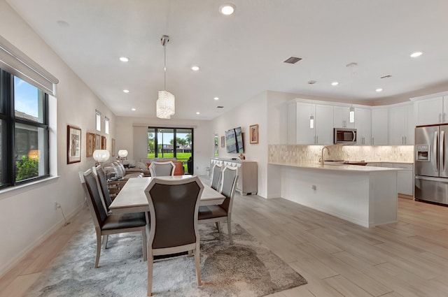 dining space with sink, a notable chandelier, and light wood-type flooring