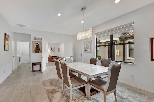 dining room with light hardwood / wood-style flooring and an inviting chandelier