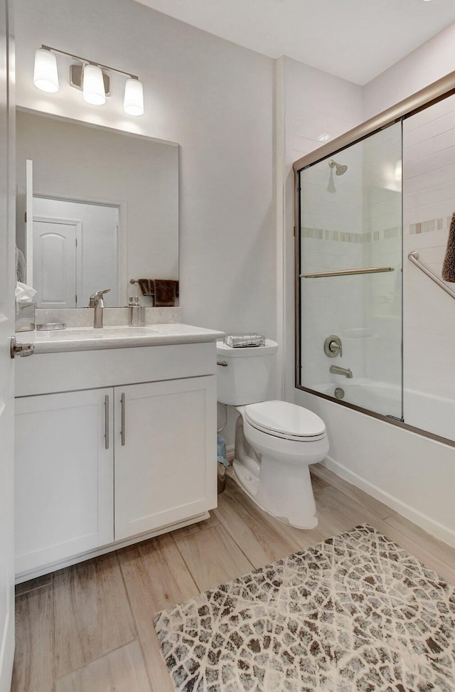 full bathroom with enclosed tub / shower combo, vanity, wood-type flooring, and toilet