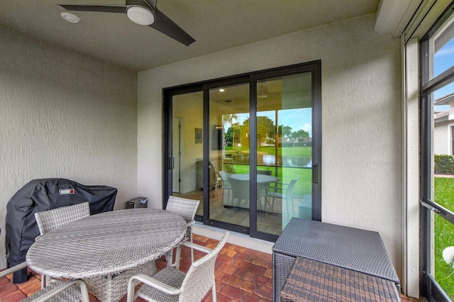 sunroom / solarium with ceiling fan and a water view